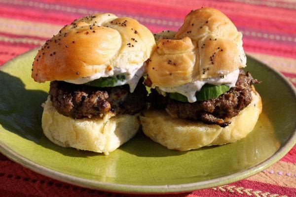 Lamb sliders with cucumber yogurt tzatziki sauce and cucumber slices.