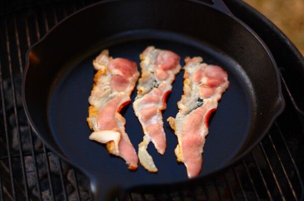 Bacon cooking on the grill in a cast iron skillet